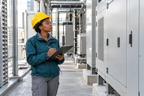 Facilities professional with a clipboard beside commercial building equipment