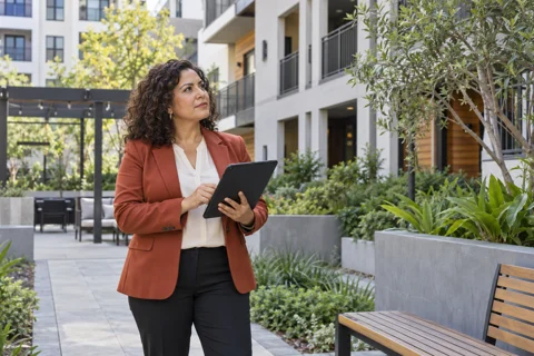 Property manager holding a tablet in an apartment courtyard